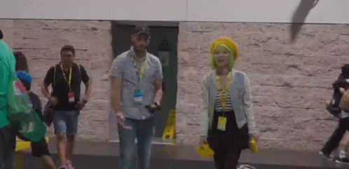 A Man And A Woman Walking In Front Of A Building GIF
