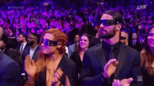A Man And A Woman Wearing Virtual Reality Glasses Are Sitting In A Crowd . GIF