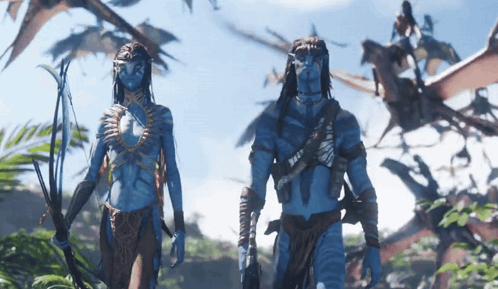 A Man And A Woman With Blue Faces Are Standing In A Forest GIF