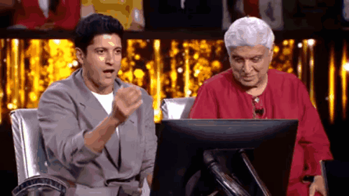 A Man And An Elderly Woman Are Sitting In Front Of A Computer Monitor . GIF