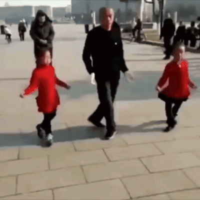 A Man And Two Children Are Walking Down A Sidewalk . GIF