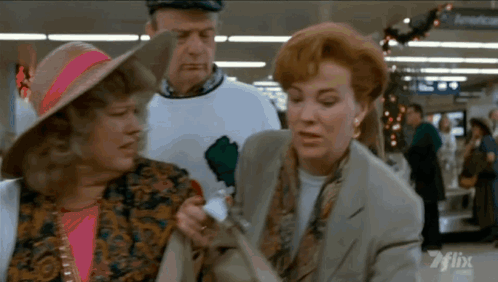 A Man And Two Women Are Standing In Front Of A Sign That Says American On It GIF