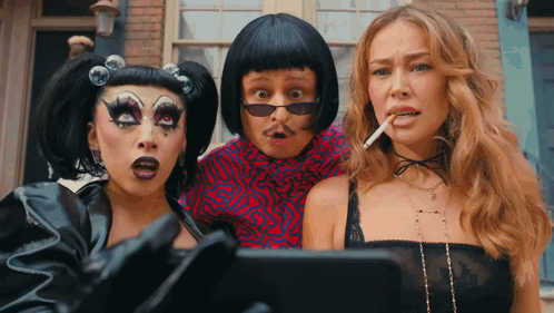 A Man And Two Women Are Standing Next To Each Other GIF