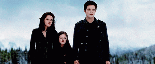 A Man And Two Women Are Standing Next To Each Other Holding Hands In The Snow . GIF