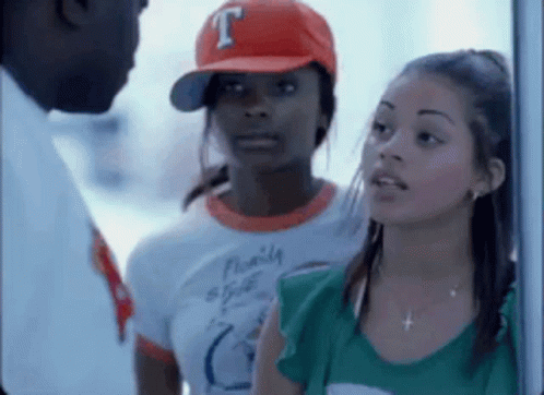 A Man And Two Women Are Standing Next To Each Other . One Of The Women Is Wearing A Baseball Cap With The Letter T On It GIF