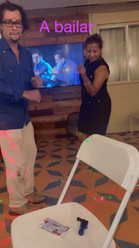 a man and woman are dancing in front of a tv that says a bailar on it