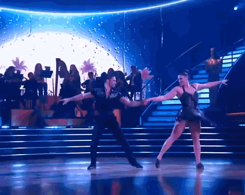 A Man And Woman Are Dancing On A Dance Floor GIF