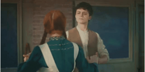 A Man And Woman Are Dancing Together In Front Of A Brick Wall . GIF