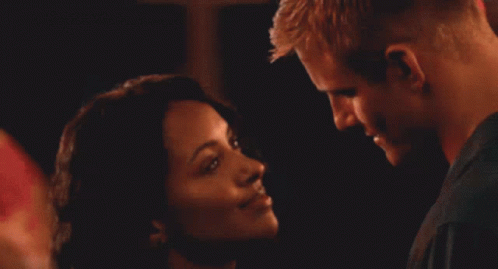 A Man And Woman Are Kissing In A Crowded Room GIF