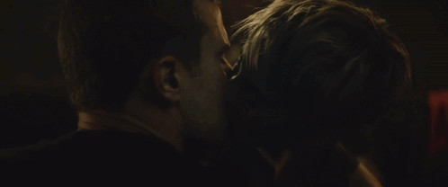 A Man And Woman Are Kissing In A Dark Room GIF