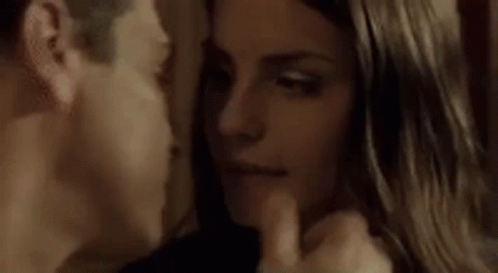 A Man And Woman Are Kissing In A Dark Room With Their Eyes Closed . GIF