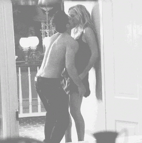 A Man And Woman Are Kissing In A Doorway . GIF