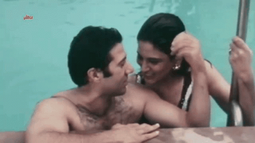 A Man And Woman Are Kissing In A Pool . GIF