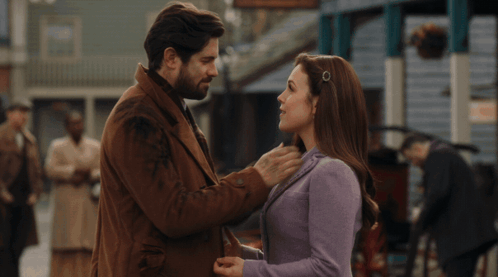 A Man And Woman Are Kissing In Front Of A Crowd Of People GIF