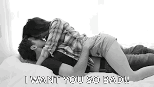 A Man And Woman Are Kissing On A Bed . GIF