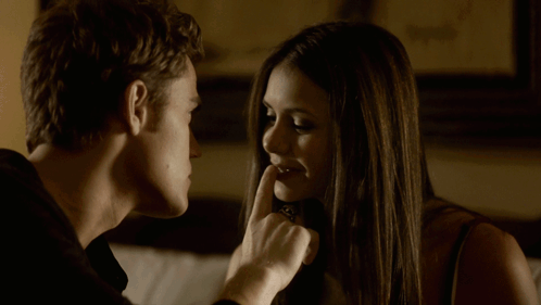 A Man And Woman Are Looking At Each Other And The Woman Is Holding Her Finger To Her Lips GIF