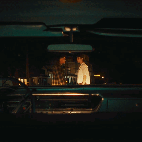 A Man And Woman Are Looking At Each Other In A Car GIF