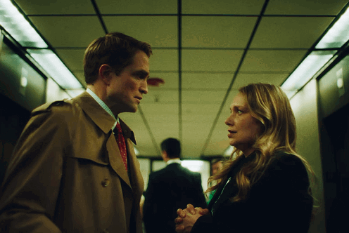 A Man And Woman Are Looking At Each Other In A Hallway GIF