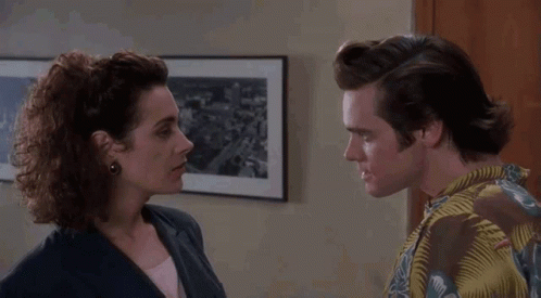 A Man And Woman Are Looking At Each Other In Front Of A Framed Picture GIF