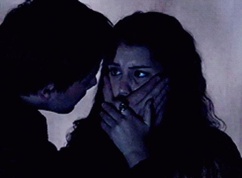 A Man And Woman Are Looking At Each Other In The Dark GIF