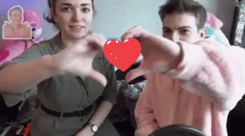 A Man And Woman Are Making A Heart Shape With Their Hands GIF