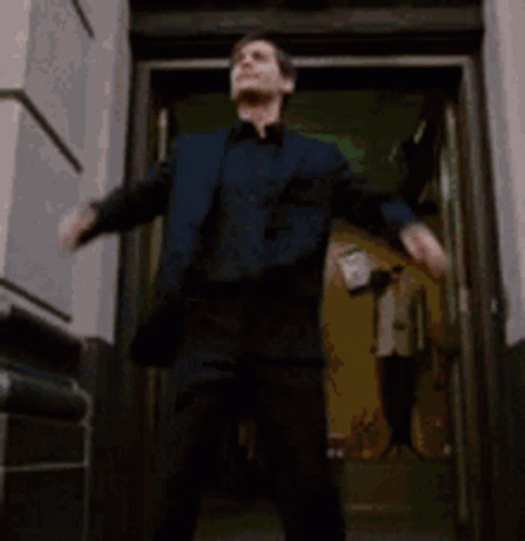 A Man And Woman Are Standing In A Doorway . GIF