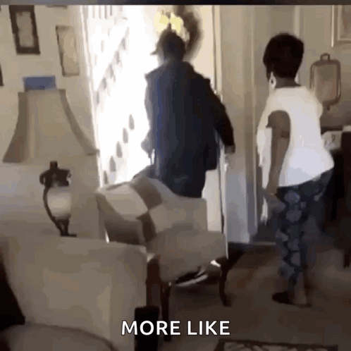 A Man And Woman Are Standing In A Living Room With The Words More Like Below Them . GIF