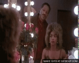 A Man And Woman Are Standing In Front Of A Mirror . GIF