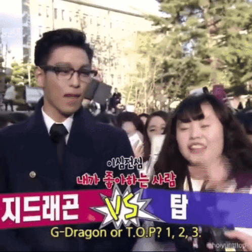 a man and woman are standing in front of a sign that says g-dragon or t.o.p? 1 2 3