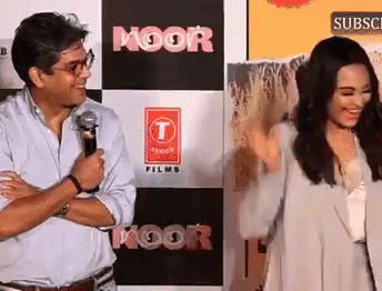 A Man And Woman Are Standing In Front Of A Sign That Says Moor Films GIF