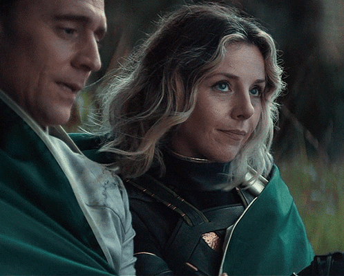 A Man And Woman Are Standing Next To Each Other And The Woman Is Smiling GIF