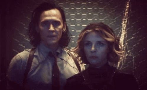 A Man And Woman Are Standing Next To Each Other In A Dark Room . GIF