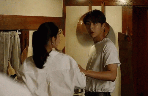 A Man And Woman Are Standing Next To Each Other In A Kitchen . GIF