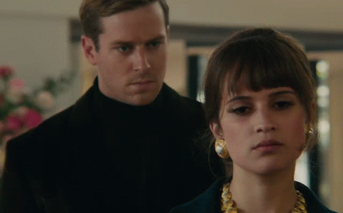 A Man And Woman Are Standing Next To Each Other GIF