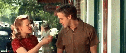 A Man And Woman Are Standing Next To Each Other On A Sidewalk . GIF