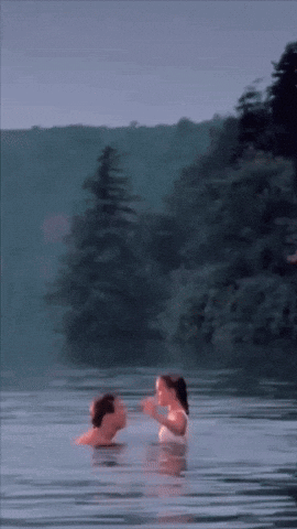 A Man And Woman Are Swimming In A Lake GIF