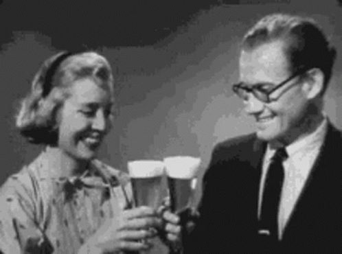 A Man And Woman Are Toasting With Beer Glasses . GIF