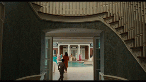 A Man And Woman Are Walking Down A Staircase Towards A Pool GIF