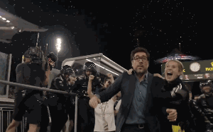 A Man And Woman Are Walking In Front Of A Sign That Says Rolex GIF