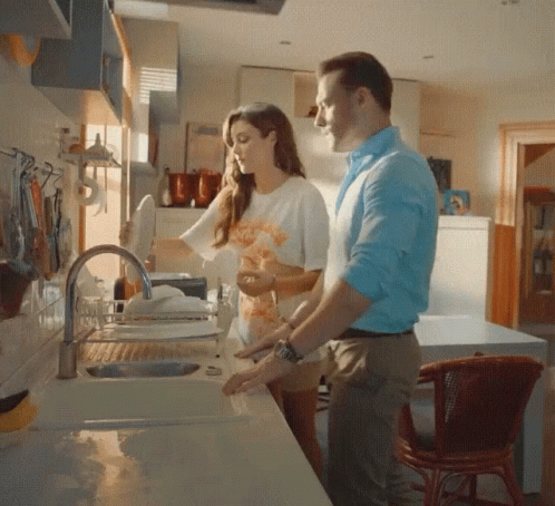 A Man And Woman Are Washing Dishes In A Kitchen Sink GIF