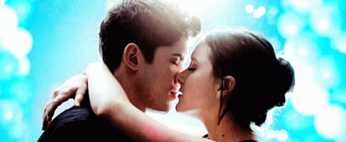 A Man And Woman Kissing In Front Of A Blue Sky GIF