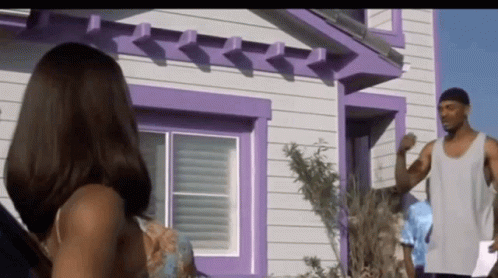A Man And Woman Standing In Front Of A Purple House GIF