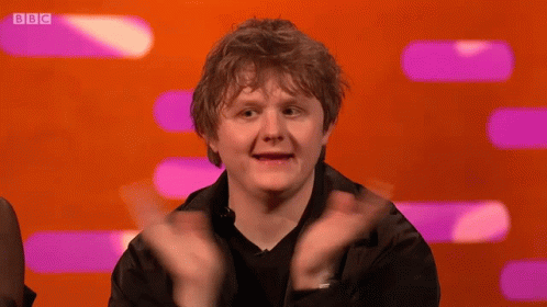 A Man Applauds In Front Of A Screen That Says Bbc On It GIF