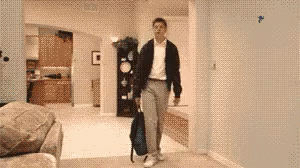 A Man Carrying A Backpack Is Walking Through A Living Room GIF