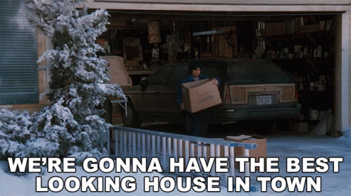 A Man Carrying A Box In Front Of A Garage With The Words We 'Re Gonna Have The Best Looking House In Town GIF
