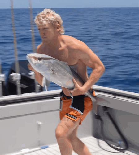 A Man Carrying A Large Fish On A Boat In The Ocean GIF