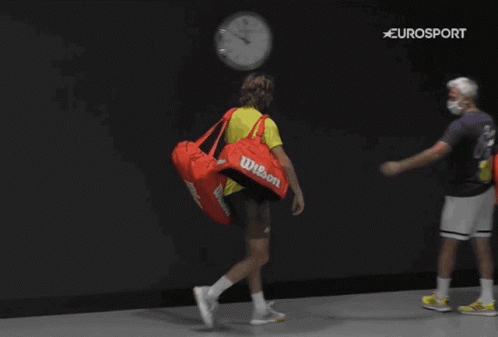A Man Carrying A Red Wilson Duffel Bag Walks With Another Man GIF