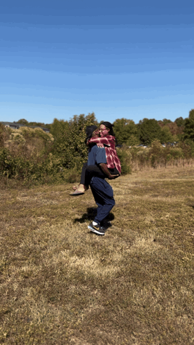 A Man Carrying A Woman In His Arms In A Field GIF