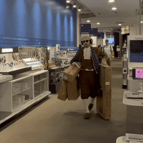 A Man Carrying Boxes In A Store With A Sign On The Wall That Says ' Electronics ' On It GIF
