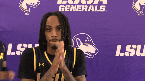 a man clapping in front of a purple banner that says lsu